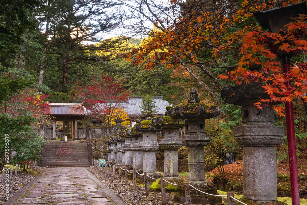 Japanese temple garden with ancient stone lanterns in the autumn, or red maple season, Nikko, Japan.