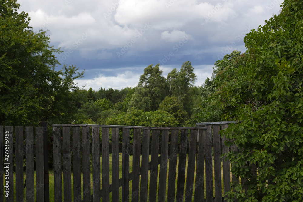 old grey wooden fence and stormy clouds on background old grey wooden fence and stormy clouds on background