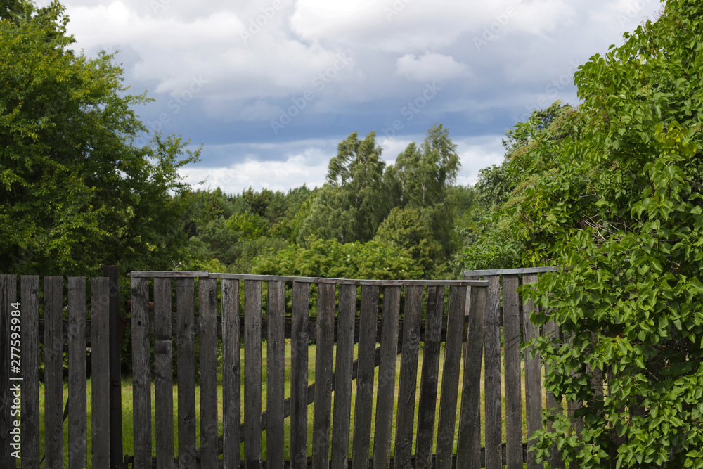 old grey wooden fence and stormy clouds on background