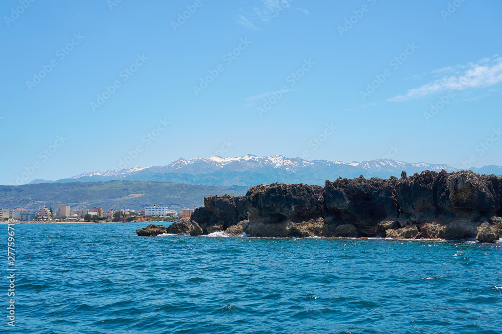Sea coast with rocks in Chania, Crete, Greece with mountains and clear blue sky on a background. Sea coast with rocks in Chania, Crete, Greece with mountains and clear blue sky on a background.