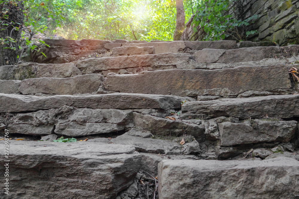 Old stone staircase, natural stone. A ray of the sun breaks through the foliage of trees. Selective focus, close up, copy space. Old stone staircase, natural stone. A ray of the sun breaks through the foliage of trees. Selective focus, close up, copy space.