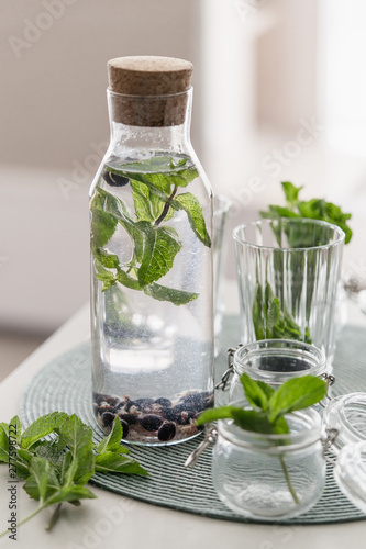 infused water fresh mint leaves and black currant berries in a glass bottle