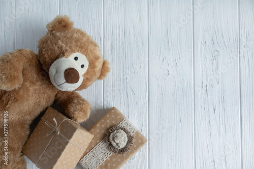 Toy bear, boxes with gifts on a light wooden background. The design of the birthday greeting card. Frame for the text of the congratulatory inscription with gift boxes and teddy bear