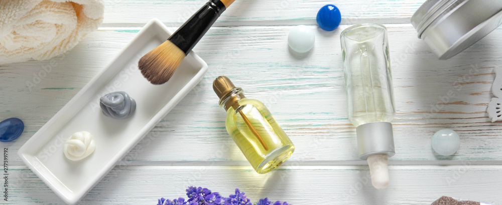 Face mask, scrub and brush for application with flowers on a wooden background. SPA concept. View from above Face mask, scrub and brush for application with flowers on a wooden background. SPA concept. View from above