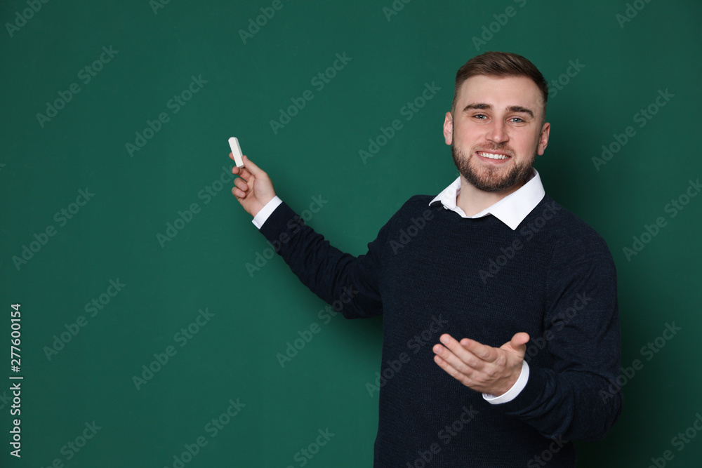 Portrait of young teacher with chalk on green background. Space for text