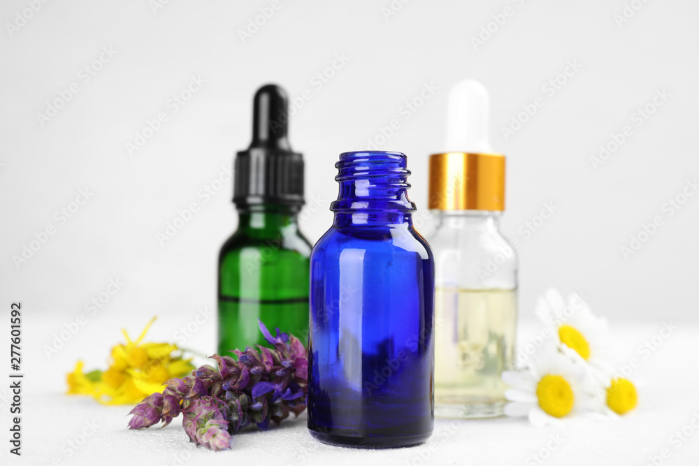 Bottles of different essential oils and wildflowers on light table Bottles of different essential oils and wildflowers on light table