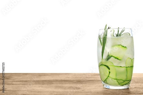 Glass of refreshing cucumber lemonade and rosemary on wooden table against white background. Summer drink