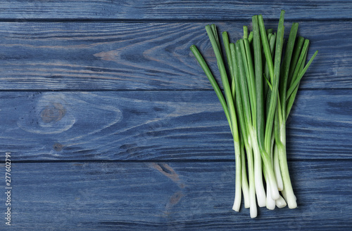 Fresh green onions and space for text on blue wooden background  top view