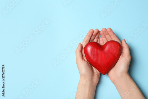 Woman holding heart on blue background, top view with space for text. Donation concept