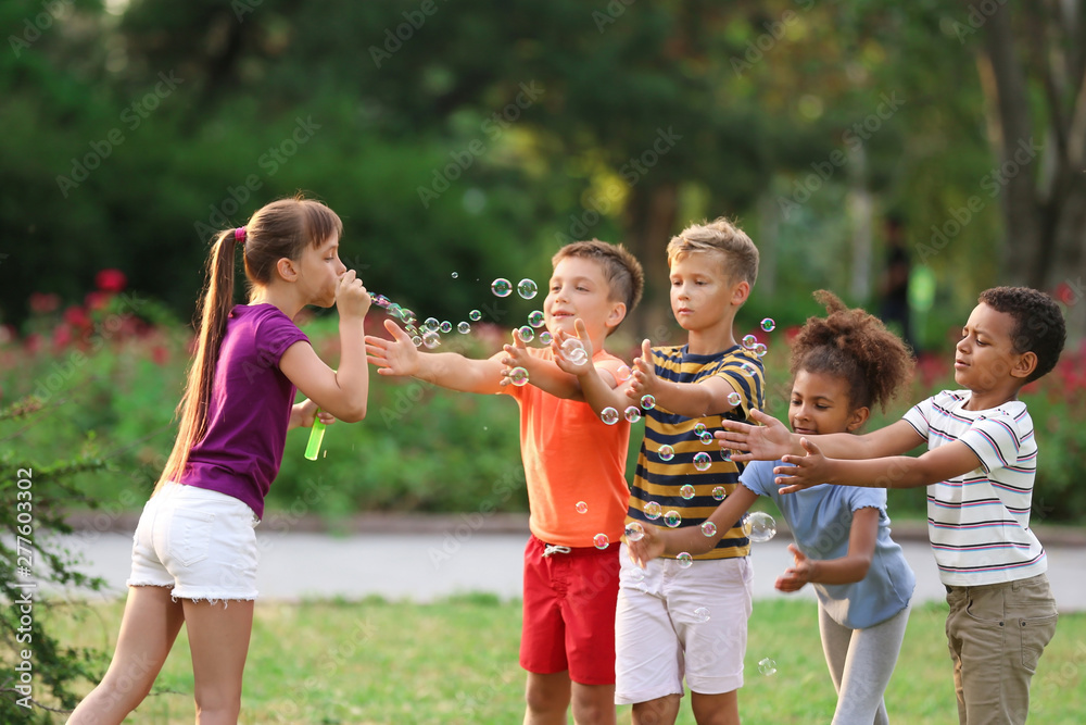 Fototapeta premium Cute little children playing with soap bubbles in park