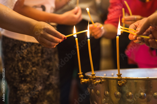 Close up somebody's hands set fire to a wax candle in the church