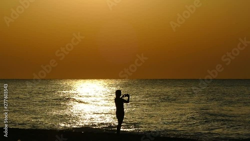 The girl is photographed against the background of the sea and dawn. Selfie on the background of the sunset. Sileet women and the ocean. photo