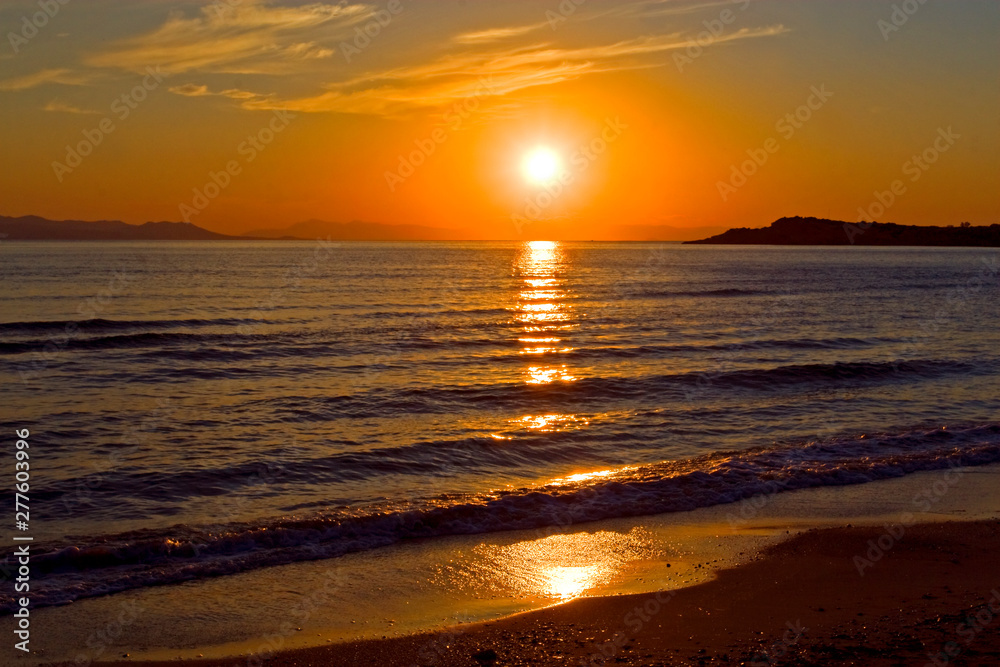 evening sun setting over the horizon at sea, greece