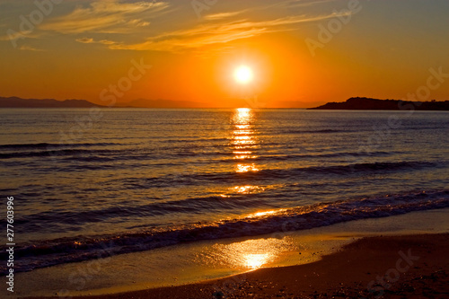 evening sun setting over the horizon at sea, greece