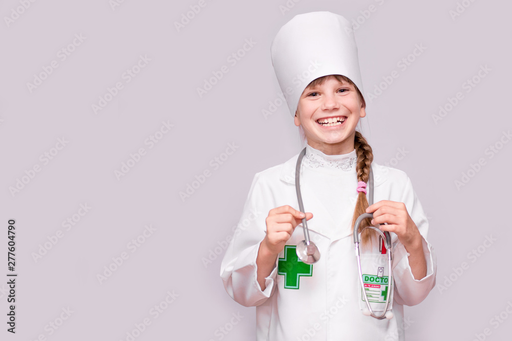 Smiling little girl in medical uniform holding stethoscope and looking at camera isolated on white Smiling little girl in medical uniform holding stethoscope and looking at camera isolated on white