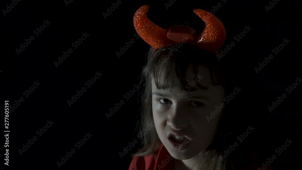 Child devil. Horror at Halloween day. Little girl in the horns and ...