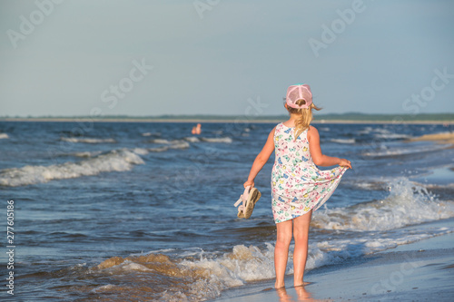 dziewczynka w letniej sukience na morskiej plaży, 