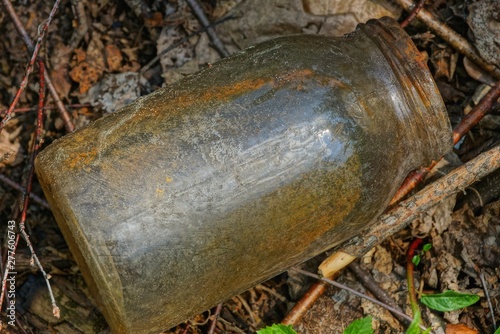 trash from one dirty glass jar is lying on the ground in nature