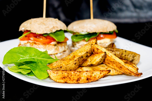  Salmon burger with rustic potatoes and rucula leaves.