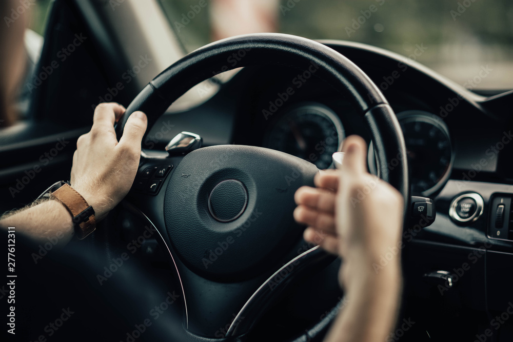 Naklejka premium driver's hands gesticulate behind the wheel of a car