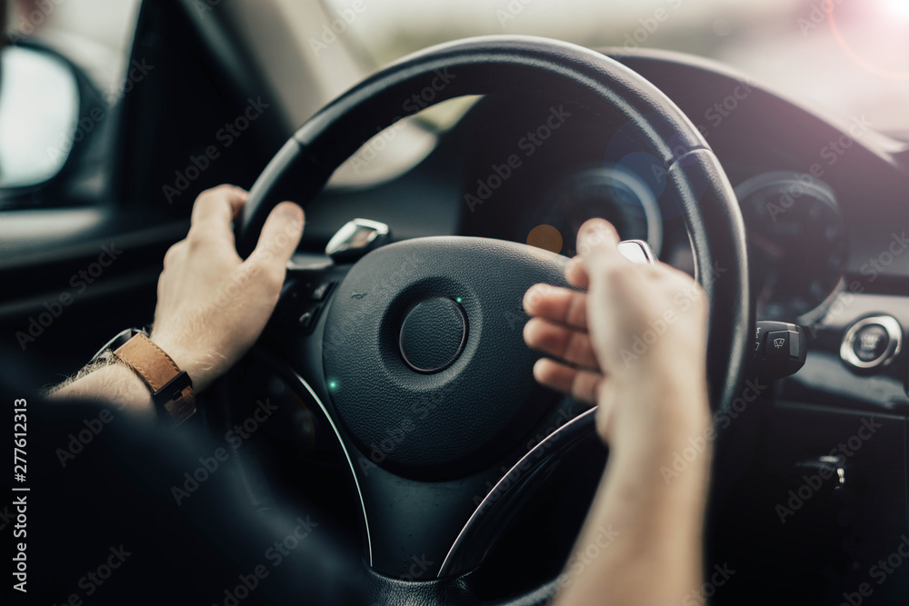 Naklejka premium driver's hands gesticulate behind the wheel of a car