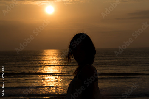 Silhouette of girl with a freedom feeling at a beautiful sunset. Happy feeling concept. Strong confidence woman feeling free with open arms under the sunrise at seaside in Colombia  Latin America.