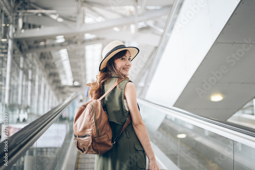 Smile Asian woman traveler walking dragging a suitcase in an airport