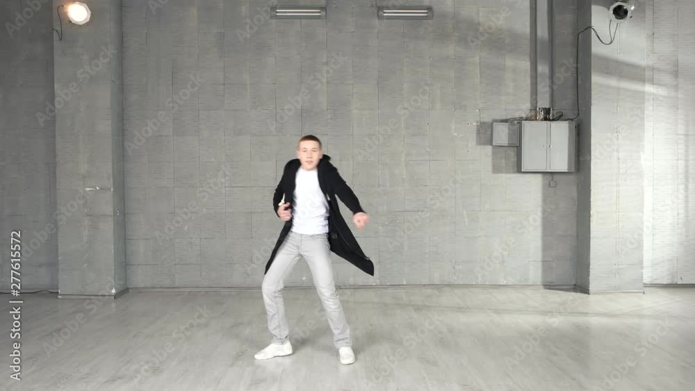 Trendy caucasian boy performing dance moves in studio. Young stylish man performing contemporary dance on grey background. Trendy caucasian boy performing dance moves in studio. Young stylish man performing contemporary dance on grey background.