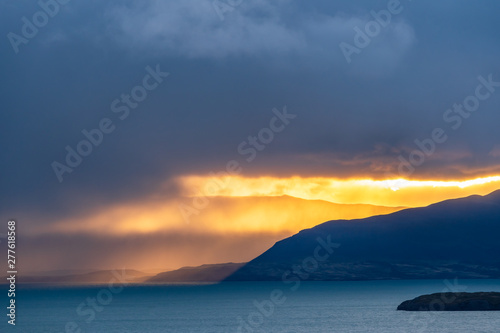 Beautiful golden orange light of sun rise over the mountain with deep blue lake in the morning in raining cloud in Torres del Paine national park  south Patagonia  Chile