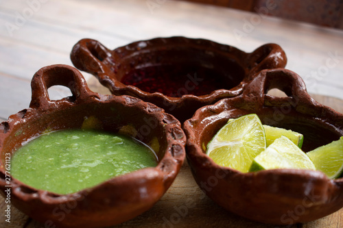 Salsa picante verde, salsa de chile de árbol y limones en cazuelas de barro son indispensables como complemento indispensable en la comidad mexicana