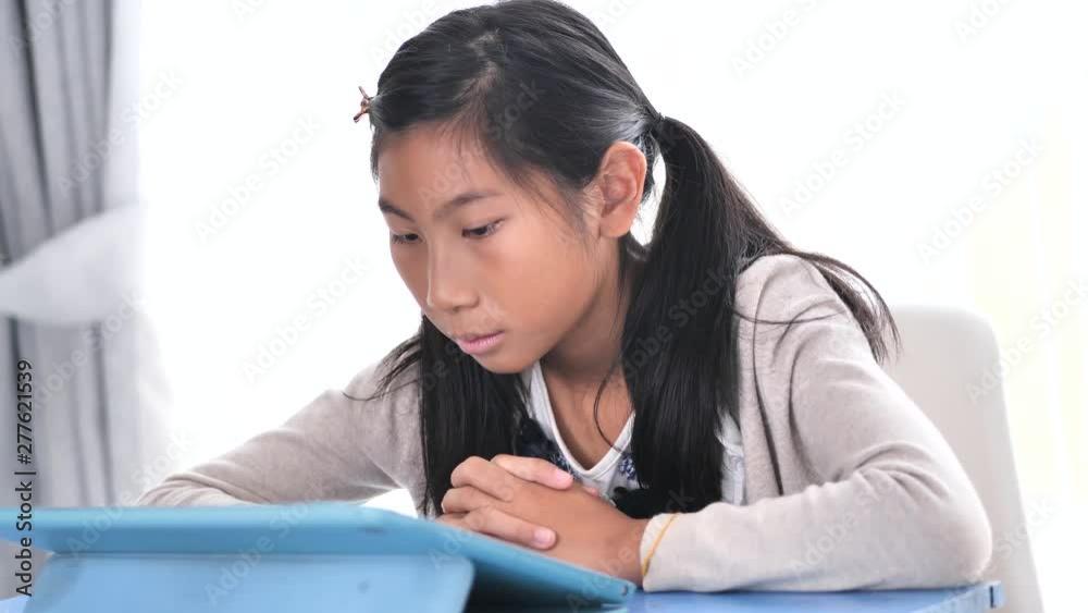Happy Asian girl using digital tablet on blue table, lifestyle concept. Happy Asian girl using digital tablet on blue table, lifestyle concept.