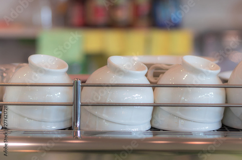 Upside down clean white coffee cups on shelf in the coffee shop