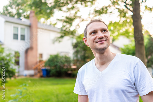 Young man happy smiling homeowner in Herndon, Northern Virginia, Fairfax county residential neighborhood in spring or summer by house backyard