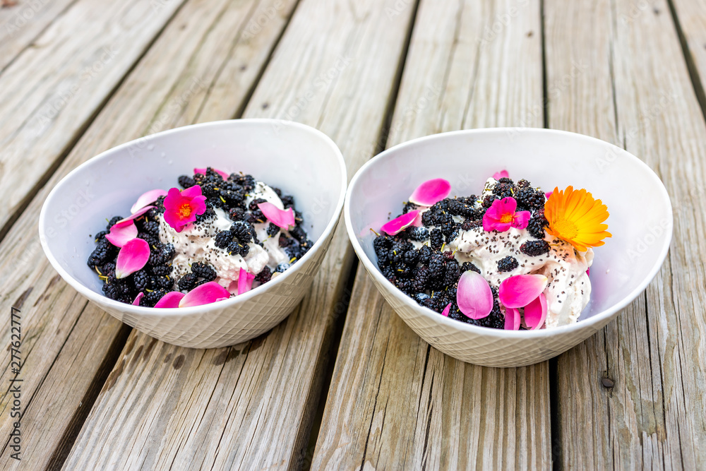 Purslane and yellow calendula flower ice cream topped with fresh black mulberries berries and chia seeds with pink rose petals Purslane and yellow calendula flower ice cream topped with fresh black mulberries berries and chia seeds with pink rose petals