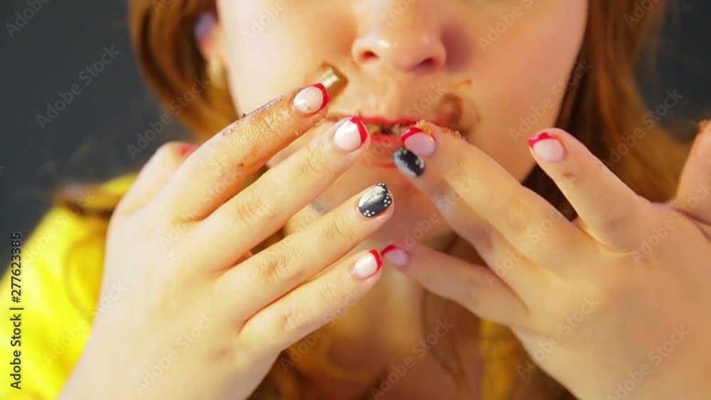 a woman with a chocolate-stained face after a diet eats cakes while no one sees