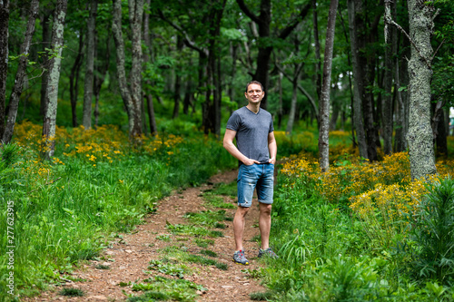 Man standing in Story of the Forest nature trail in Shenandoah Blue Ridge appalachian mountains by yellow flowers on path
