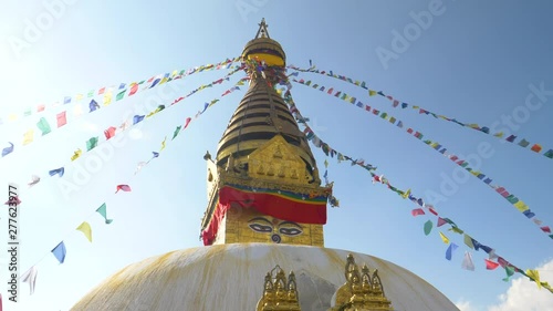 SLOW MOTION, LENS FLARE: Swayambhunath stupa and prayer flags moving in the strong winds blowing in Nepal. Breathtaking view of an ancient hindu temple and colorful ribbons on a sunny day in Kathmandu