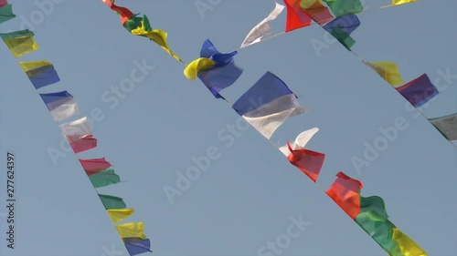 SLOW MOTION CLOSE UP: Multicolored prayer flags hanging off ropes suspended from Monkey Temple flutter in the strong wind blowing across Kathmandu. Beautiful shot of colorful flags in moving in breeze