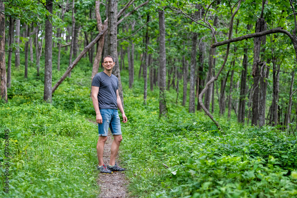 Young happy man standing on Appalachian nature trail in Shenandoah Blue Ridge mountains with green grass lush foliage on path Young happy man standing on Appalachian nature trail in Shenandoah Blue Ridge mountains with green grass lush foliage on path
