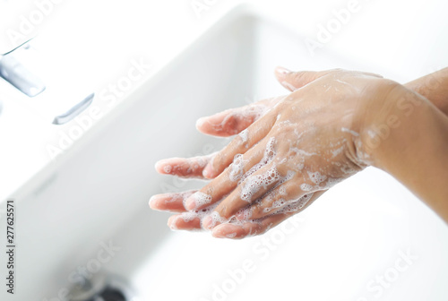 Closeup woman's hand washing with soap in bathroom, selective focus