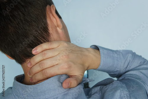 young man is holding his neck. the concept of health, pain in the neck. The patient complains of a sore neck. instability of the vertebrae. fatigue at work photo