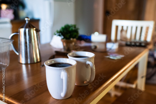 Closeup of two cups with coffee or puerh black tea with stainless steel french press on wooden rustic table in country home