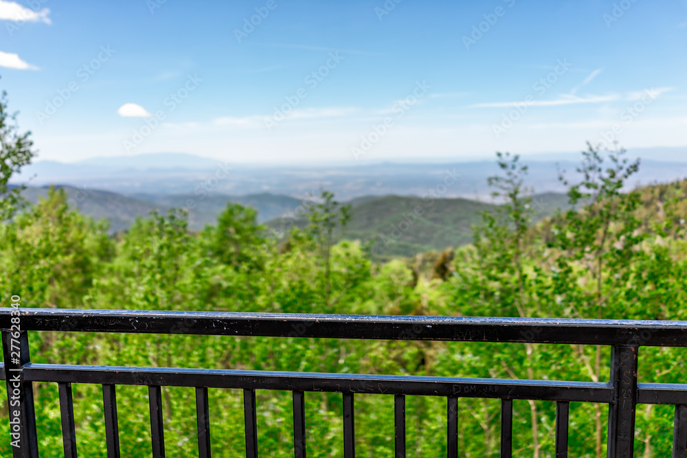 Santa Fe National Forest Sangre de Cristo mountains with horizon background and foreground of fence railing and green aspen trees in spring