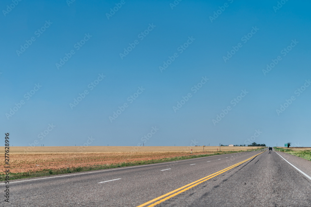 Brownfield, USA Texas countryside rural town historic farm road view from 380 highway with prairie dry grass field and blue sky