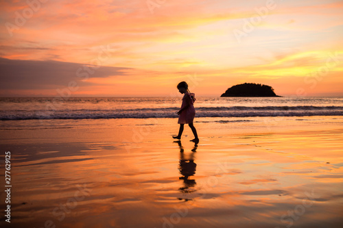 Cute little girl walking on the beach. Sunset time. Kid having fun in holiday vacation with back sun light - Youth  lifestyle  travel and happiness concept