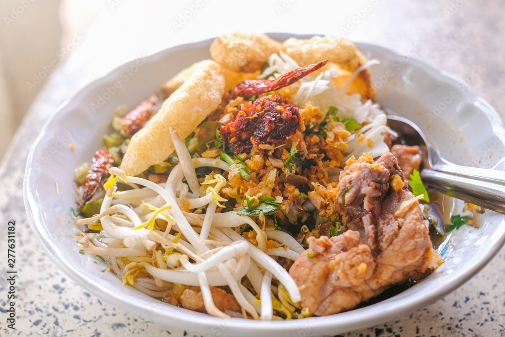 rice noodle with pork , bean sprouts, crispy pork skin, chili powder and clear soup is served at street food in Chiangmai, Thailand rice noodle with pork , bean sprouts, crispy pork skin, chili powder and clear soup is served at street food in Chiangmai, Thailand