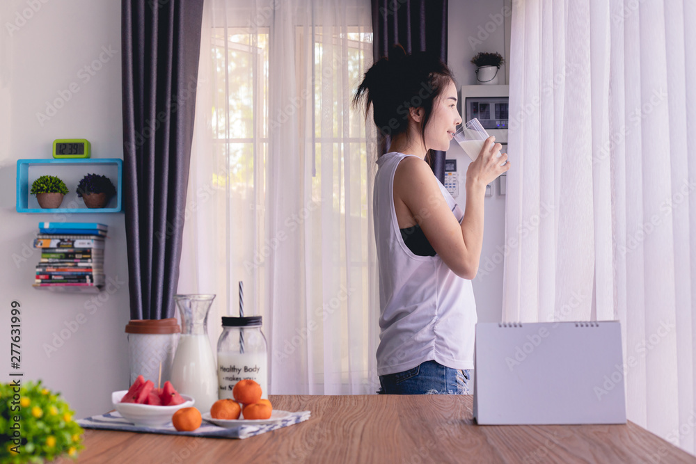 Standing woman drinking milk in living room at home. Standing woman drinking milk in living room at home.
