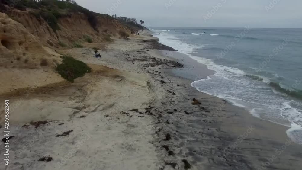 Moving Arial shot, birds eye view, shot with a drone of the ocean waves breaking on the white beach next to a busy highway. Moving Arial shot, birds eye view, shot with a drone of the ocean waves breaking on the white beach next to a busy highway.