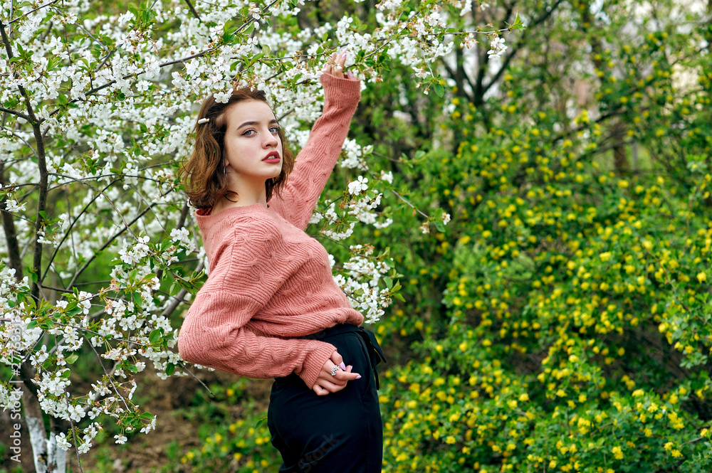 Portrait of a beautiful young girl in a blooming garden .