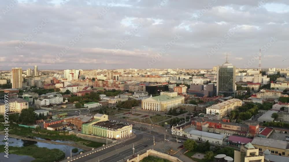 Aerial panoramic view of Chelyabinsk city, sunny evening and the main embankment of the river Miass; drone flying up